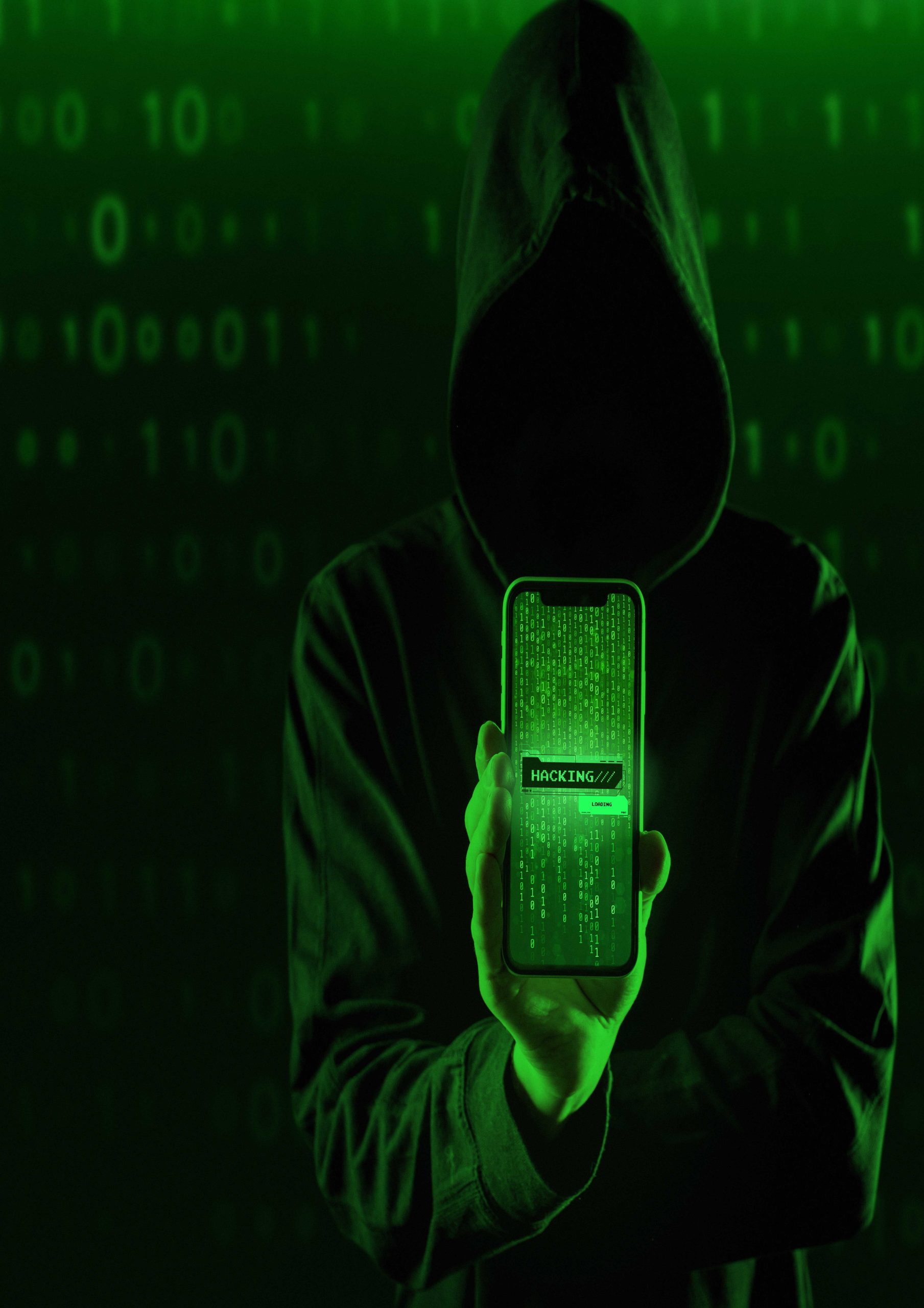 A hooded individual holding a mobile phone with a green overlay.
